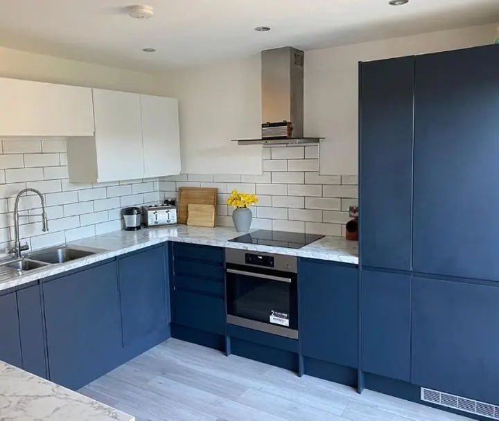 The finished kitchen: navy units, white tiles and marble-effect worktops