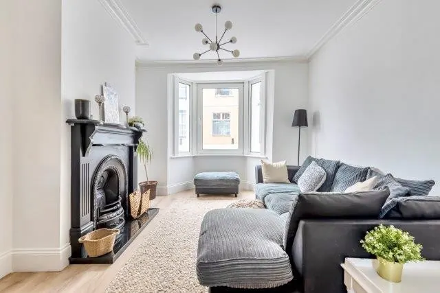 After: the same room finished in white, with a fireplace and wooden floor